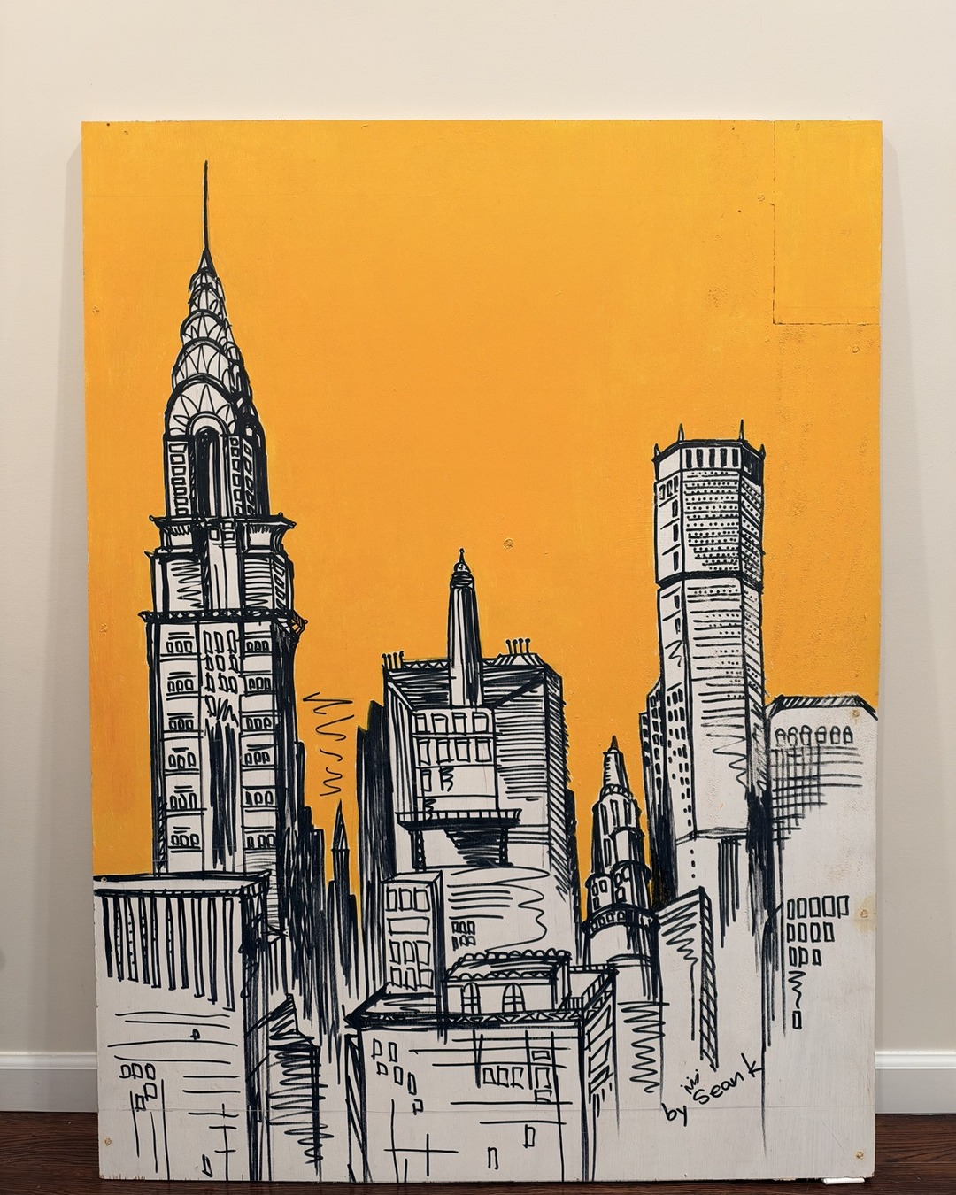 Large golden-yellow wood panel drawing of the New York City skyline by Sean Kwac
